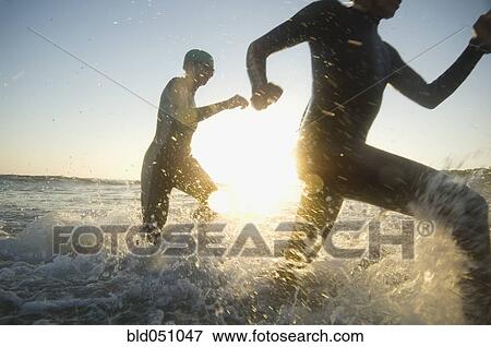 Multi-ethnic swimmers running in surf View Large Photo Image Stock Photo - Multi-ethnic swimmers running in surf. Fotosearch