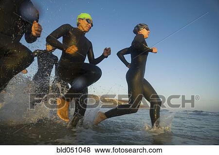Multi-ethnic swimmers running in surf View Large Photo Image Stock Photo - Multi-ethnic swimmers running in surf. Fotosearch
