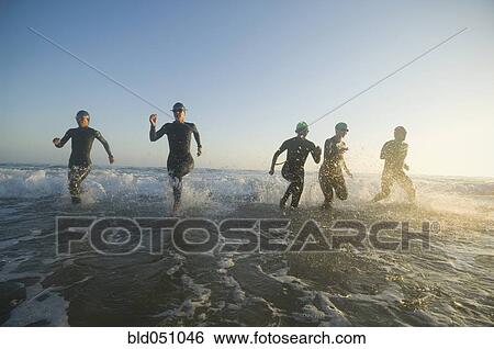 Multi-ethnic swimmers running in surf View Large Photo Image Stock Photograph - Multi-ethnic swimmers running in surf. Fotosearch