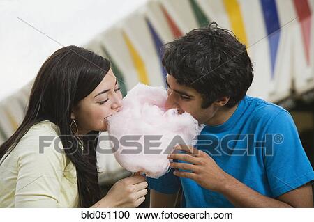 Stock Image - Multi-ethnic teenaged couple eating cotton candy. Fotosearch