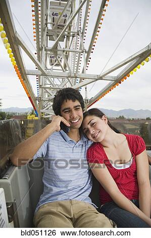 Stock Photograph - Multi-ethnic teenaged couple on carnival ride. Fotosearch