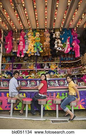 Picture - Multi-ethnic teenaged friends at carnival booth. Fotosearch