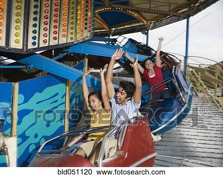 Stock Image - Multi-ethnic teenaged friends on carnival ride. Fotosearch