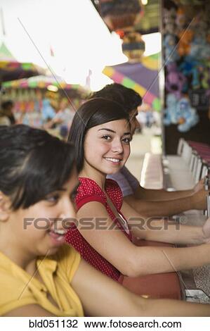 Stock Image - Multi-ethnic teenaged friends playing carnival game. Fotosearch