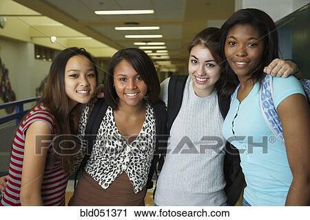 Stock Image - Multi-ethnic teenaged girls hugging in school hallway. Fotosearch