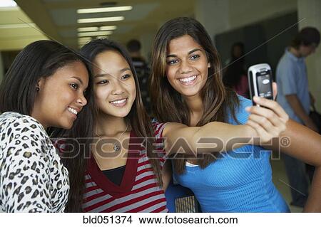 Picture - Multi-ethnic teenaged girls taking own photograph. Fotosearch