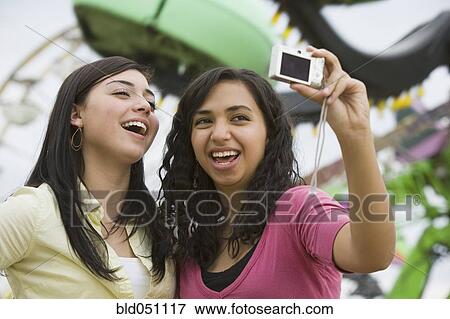 Stock Photo - Multi-ethnic teenaged girls taking own photograph. Fotosearch