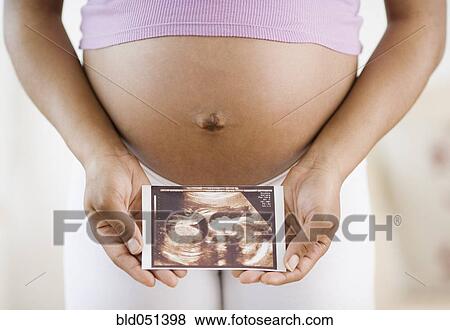 Stock Photo - Pregnant African American woman holding ultrasound printout. Fotosearch