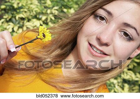 Young woman holding flower View Large Photo Image Stock Photo - Young woman holding flower. Fotosearch