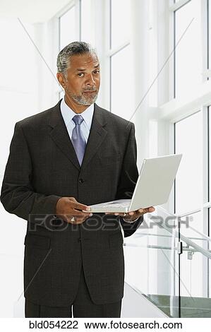 African businessman holding laptop View Large Photo Image Stock Image - African businessman holding laptop. Fotosearch