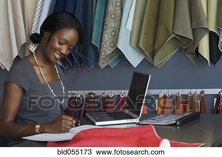 Stock Image - African businesswoman writing on calendar. Fotosearch