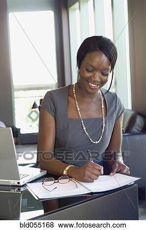 Stock Photo - African businesswoman writing on calendar. Fotosearch