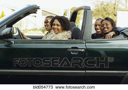 Stock Image - African couples driving in convertible car. Fotosearch