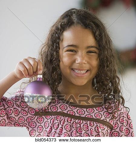 Stock Image - African girl holding Christmas ornament. Fotosearch