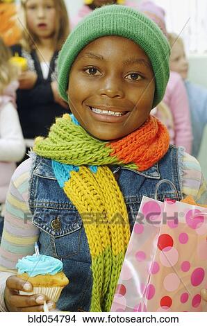 Picture - African girl holding cupcake and gift bag. Fotosearch