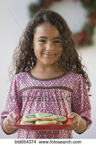 Picture - African girl holding plate of cookies. Fotosearch
