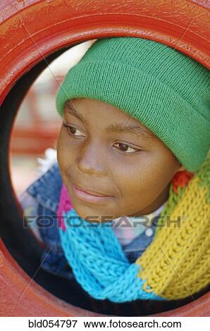 Stock Photo - African girl leaning head through tire swing. Fotosearch
