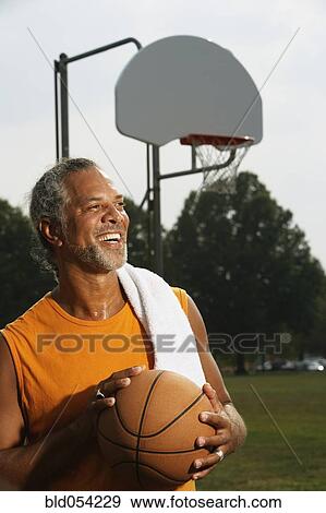 Stock Photo - African man holding basketball. Fotosearch