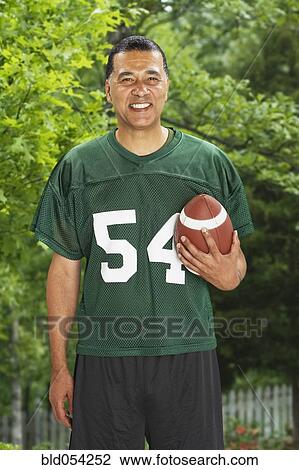 Stock Image - African man holding football. Fotosearch