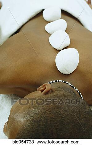 Stock Photo - African man receiving spa stone treatment. Fotosearch