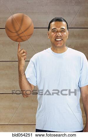 Stock Image - African man spinning basketball on finger. Fotosearch