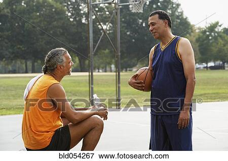 Stock Photo - African men talking on basketball court. Fotosearch
