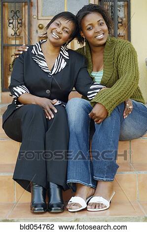 Stock Image - African mother and adult daughter hugging. Fotosearch