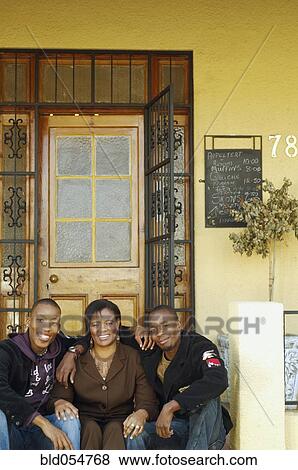 Stock Photo - African mother and adult sons on porch steps. Fotosearch
