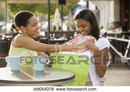 Stock Photo - African mother holding new clothes up to daughter. Fotosearch