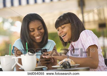 Stock Photography - African teenaged girls looking at cell phone. Fotosearch