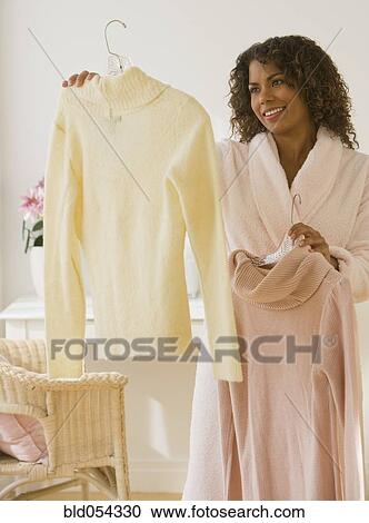 Stock Image - African woman deciding what to wear. Fotosearch
