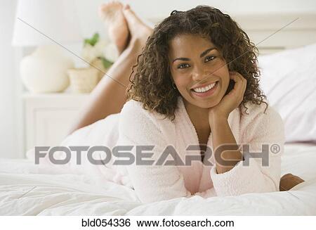 Stock Photograph - African woman laying on bed. Fotosearch
