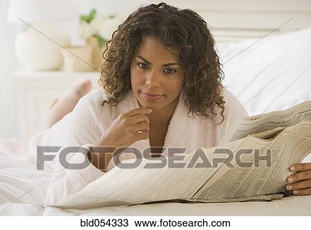 Stock Image - African woman reading newspaper. Fotosearch