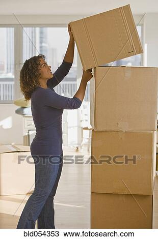 Stock Image - African woman stacking moving boxes. Fotosearch