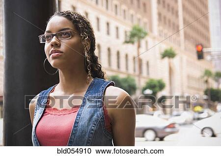 Stock Image - African woman standing on sidewalk. Fotosearch
