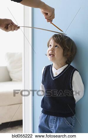 Stock Image - Asian boy having height measured on wall. Fotosearch