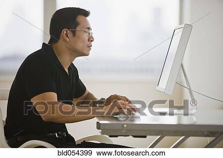 Asian businessman looking at computer View Large Photo Image Stock Photo - Asian businessman looking at computer. Fotosearch