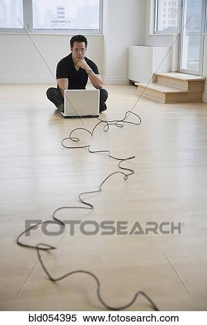Stock Photography - Asian businessman looking at laptop on floor. Fotosearch
