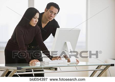 Stock Photo - Asian businesspeople looking at computer. Fotosearch