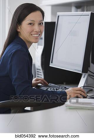 Asian businesswoman sitting at computer View Large Photo Image Stock Image - Asian businesswoman sitting at computer. Fotosearch