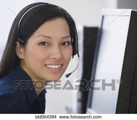 Picture - Asian businesswoman wearing headset. Fotosearch