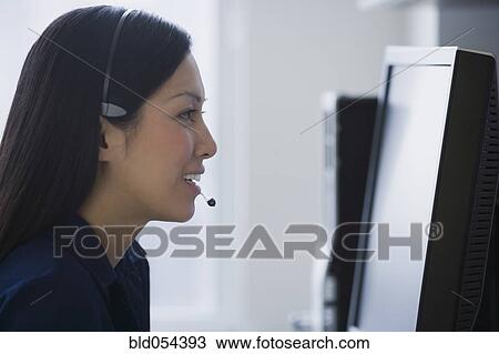 Stock Image - Asian businesswoman wearing headset. Fotosearch