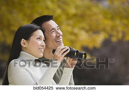 Asian couple holding binoculars View Large Photo Image Stock Photography - Asian couple holding binoculars. Fotosearch