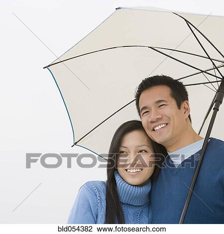 Asian couple hugging under umbrella View Large Photo Image Stock Image - Asian couple hugging under umbrella. Fotosearch
