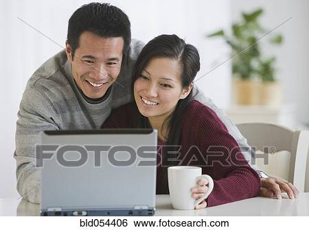 Stock Photograph - Asian couple looking at laptop. Fotosearch