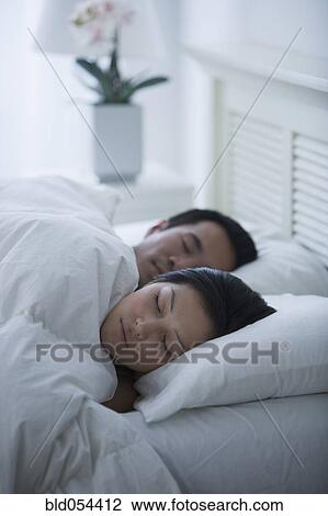 Stock Image - Asian couple sleeping in bed. Fotosearch