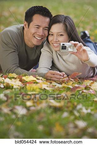 Picture - Asian couple taking own photograph. Fotosearch