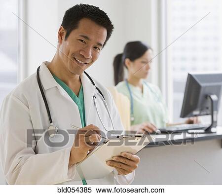 Stock Photography - Asian male doctor holding chart. Fotosearch