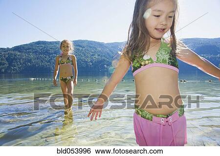 Stock Photograph - Asian sisters wading in lake. Fotosearch