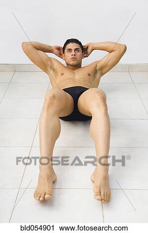 Stock Image - Bare-chested Hispanic man doing sit-ups. Fotosearch